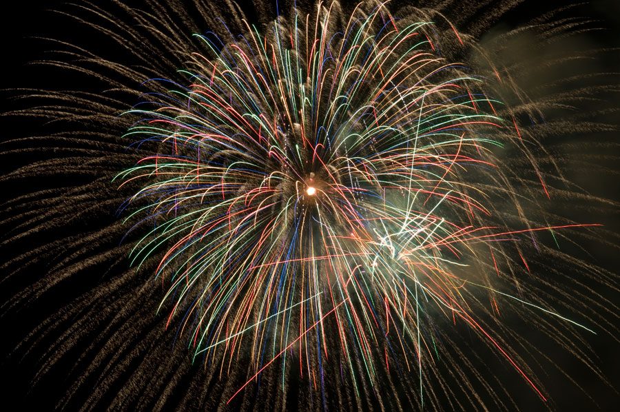 Multi-colored fireworks explode in the night sky.