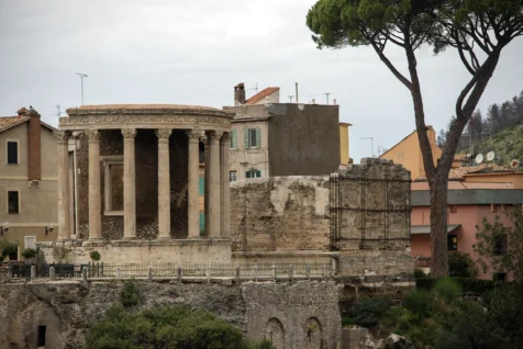 An old structure, trees and assorted buildings at the exit of Parco Villa Gregoriana in Tivoli, Italy, 2022.