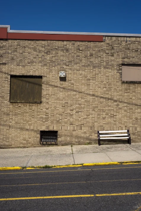 A brick building and white bench in Palisades Park, New Jersey, 2016.