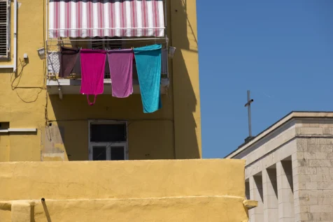 Colorful towels hang from a balcony on a sunny afternoon in Split, Croatia, 2019.