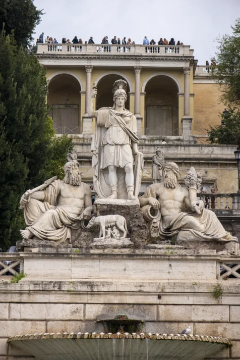 A fountain, statues and people at Piazza del Popolo in Rome, Italy, 2022.