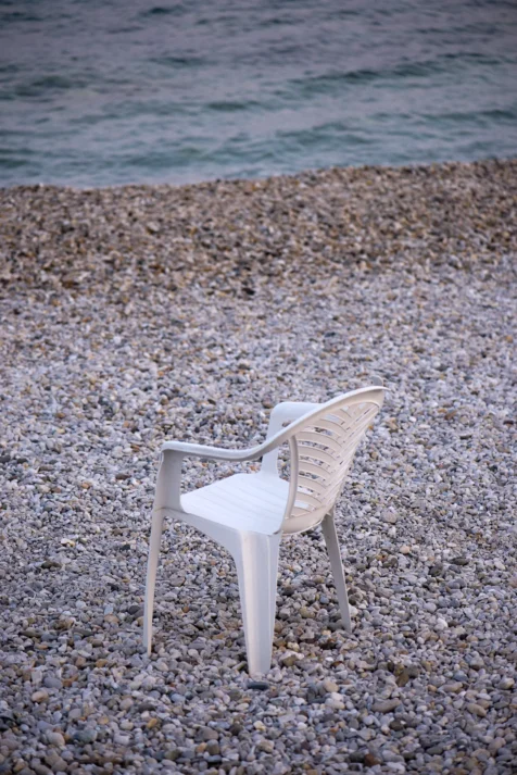 Plastic chair on rocky beach at dusk in Split, Croatia, 2019.