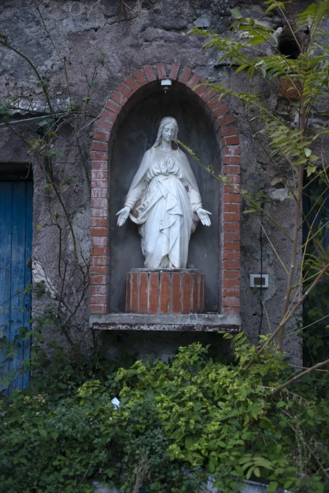 A sculpture of St. Mary near a dilapidated building in Tivoli, Italy, 2022.