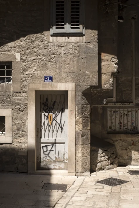 Sunlit, graffiti-covered door in Old Town, Split, Croatia, 2019.