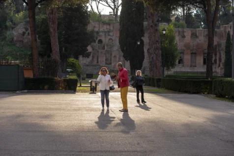 A trio of people in sunlight at the Baths of Caracalla in Rome, Italy, 2022.