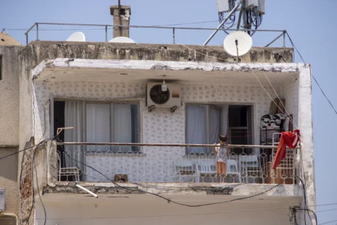 A boy stands on the balcony of a dilapidated building in Antalya, Turkey, 2023.