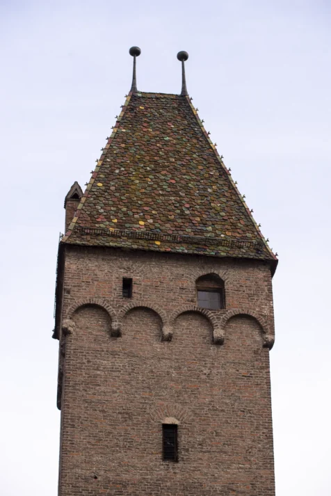 A brick tower with multi-colored roof tiles in Ulm, Germany, 2023.