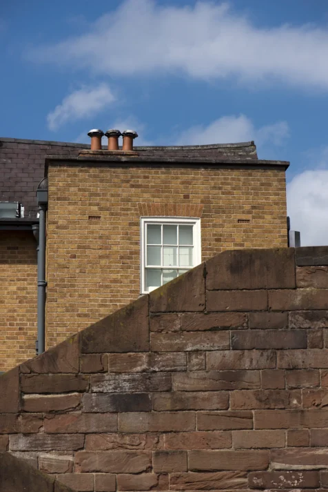A brick building and part of the Roman walls on a sunny afternoon in Chester, England, 2017.