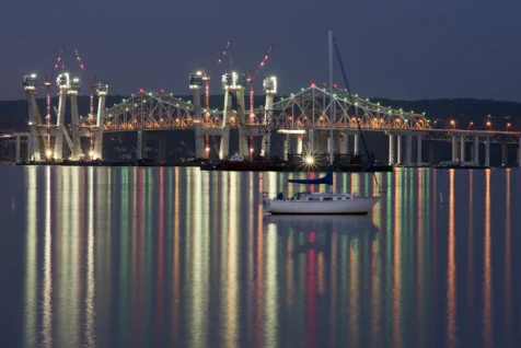 A long exposure of a boat and the Governor Mario M. Cuomo Bridge under construction at night in Nyack, New York, 2016.