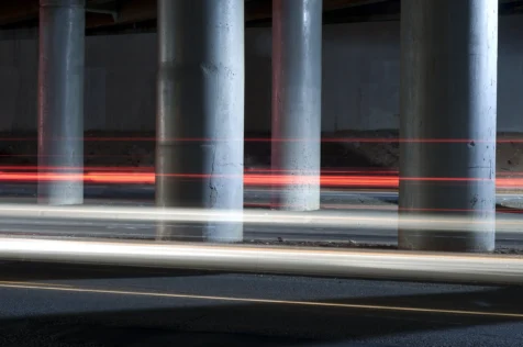 Passing cars create light trails among concrete pillars at night in Nyack, New York, 2015.