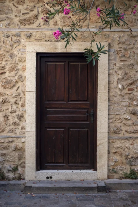 A wooden door and pink flowers in Old Town, Antalya, Turkey, 2024.