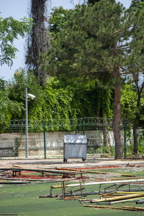 A dumpster, security camera and barbed wire fence on a sunny afternoon in Antalya, Turkey, 2023.