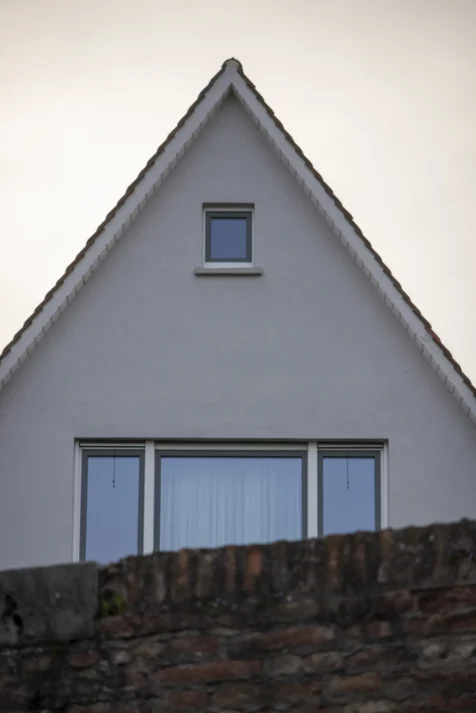 A grey house and brick wall in Ulm, Germany, 2023.
