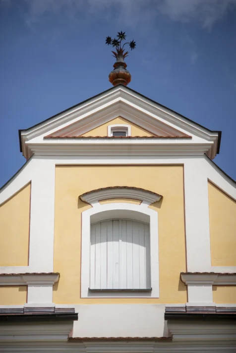 Metal flowers and a pot on the roof of a yellow building in Wiblingen, Germany, 2023.