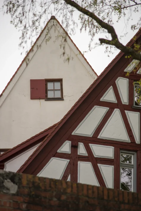 A pair of buildings behind a brick wall in Ulm, Germany, 2023.