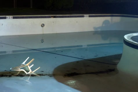 Nearly empty pool and overturned plastic chair at condo complex in Valley Cottage, New York, 2014.