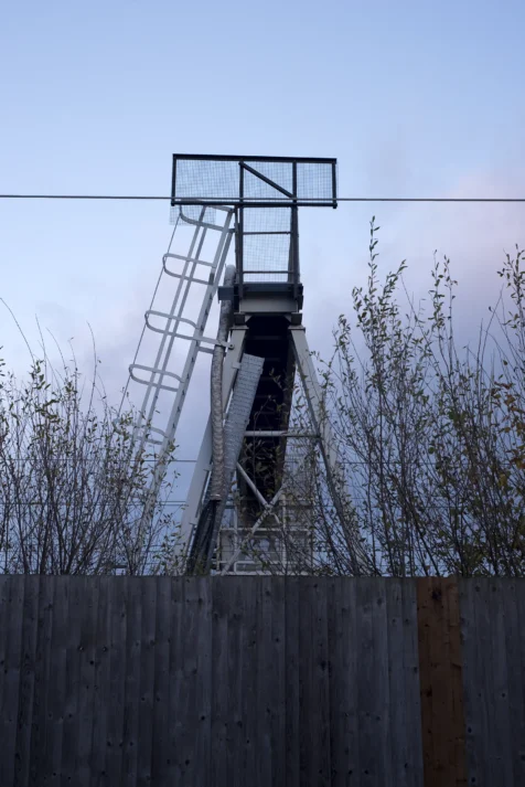 A structure and fence near train tracks at dusk in Warrington, England, 2017.