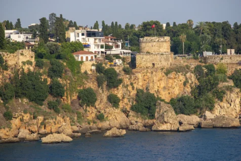 A Turkish flag on a rock tower, buildings and cliffs in Antalya, Turkey, 2023.