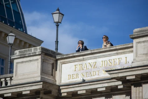 A couple women look out from terrace in Vienna, Austria, 2023.