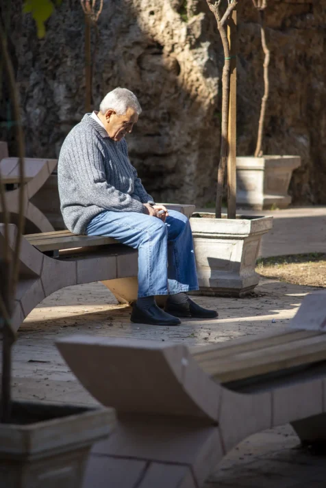 A man looks at his phone while sitting on a bench near Old Town in Antalya, Turkey, 2024.