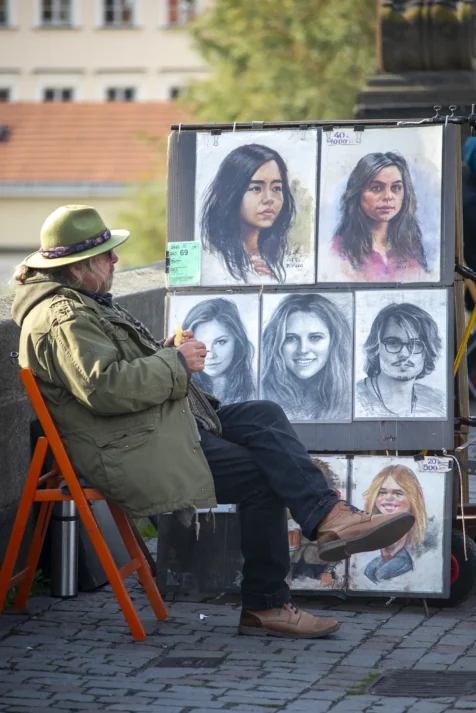 A portrait artist smokes a cigarette on Charles Bridge in Prague, Czech Republic.